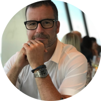 Headshot of a smiling client with glasses resting his chin on his hand