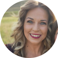 Headshot of a smiling client with long highlighted brown hair outdoors